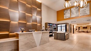 A modern hotel lobby with a reception desk, marble counter, and a seating area with tables and chairs.