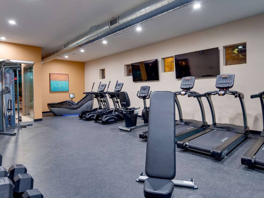 Un gimnasio con cintas de correr, máquinas de pesas y mancuernas.