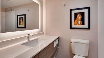 A bathroom with a white sink, a mirror, a framed picture of a horse, and a toilet.