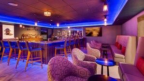 A bar area with a bar counter, multiple chairs, and a sofa.