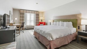 A hotel room with a large bed, a desk, a chair, a television, and a window with curtains. - Country Inn & Suites by Radisson, Green Bay, WI (Green Bay)