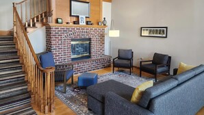 A living room with a fireplace, a staircase, and a sofa. - Country Inn & Suites by Radisson, Green Bay, WI (Green Bay)
