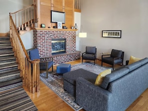A living room with a fireplace, a staircase, and a sofa. - Country Inn & Suites by Radisson, Green Bay, WI (Green Bay)