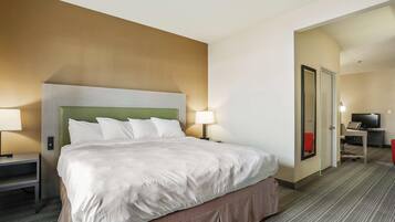 A hotel room with a large bed, bedside tables, a desk with a chair, and a television.
