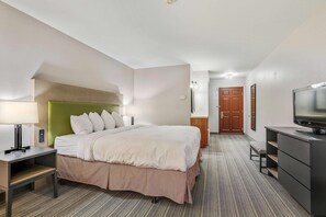 Een hotelkamer met een bed, nachtkastje, lamp, televisie en een bureau met lades.