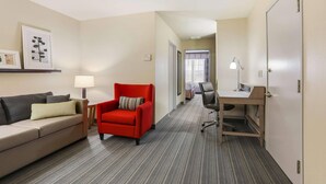 A hotel room with a sofa, a red armchair, a desk, and a lamp. - Country Inn & Suites by Radisson, Green Bay, WI (Green Bay)