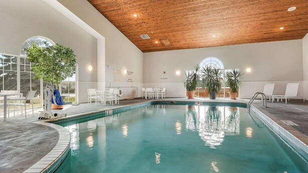An indoor swimming pool with a wooden ceiling, white walls, and potted plants. - Country Inn & Suites by Radisson, Green Bay, WI (Green Bay)