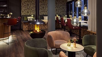 A modern lounge area with a central fire feature, patterned seating, and pendant lighting.