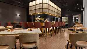 Un restaurante moderno con barra, suelo de madera y asientos acolchados.