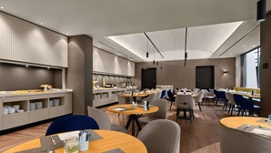 Un comedor moderno con mesas redondas, sillas y una mesa de buffet.
