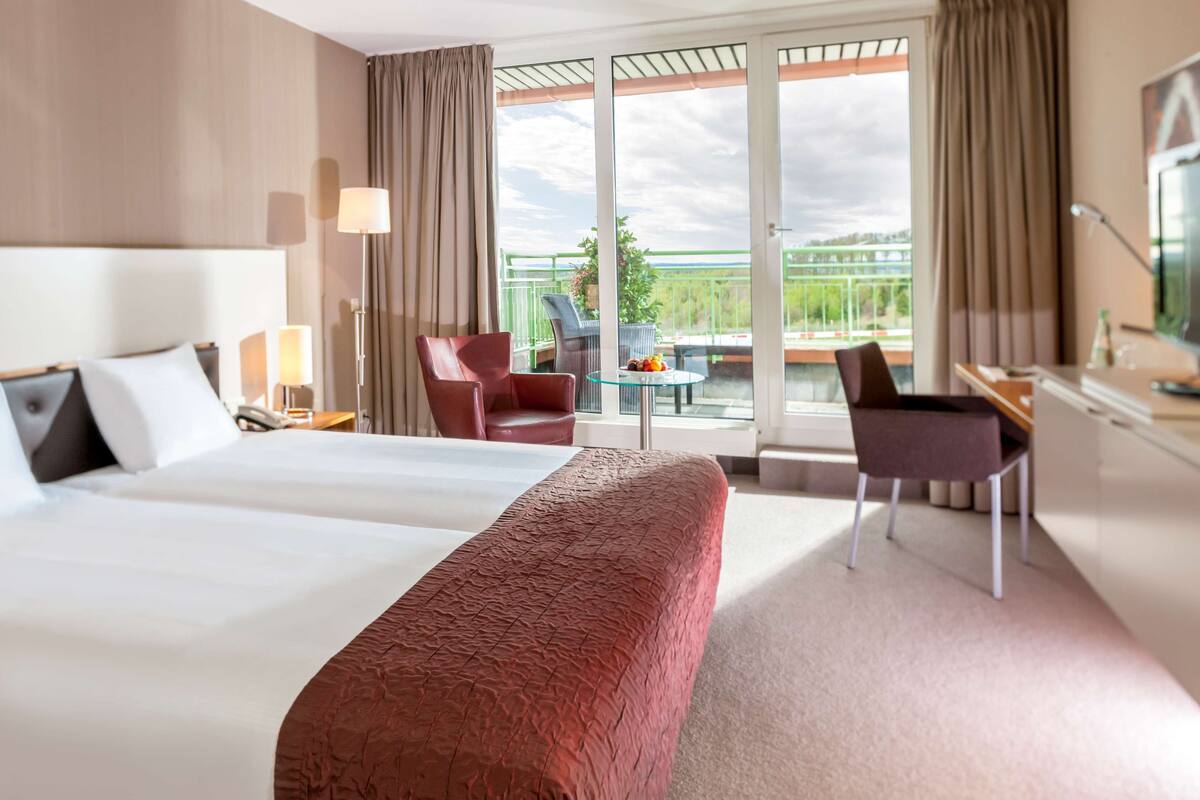 Una habitación de hotel con una cama grande, un escritorio, una silla y un balcón con vistas.
