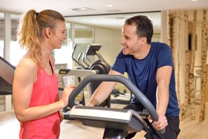 Un gimnasio con equipo de ejercicio y una persona sosteniendo una botella de agua.