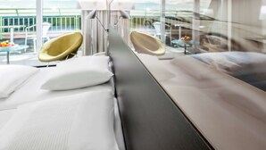 Habitación de hotel moderna con una cama grande, dos sillones y vistas al exterior.