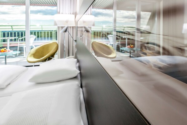 Habitación de hotel moderna con una cama grande, dos sillones y vistas al exterior.