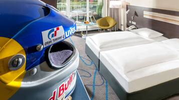 Relax in a stylish room with a comfortable bed, a small table, and a window offering a view of the outside.