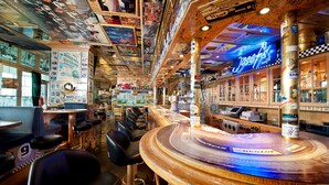 A bar area with a counter, bar stools, and a neon sign. - Dorint Am Nürburgring Hocheifel (Nuerburg)