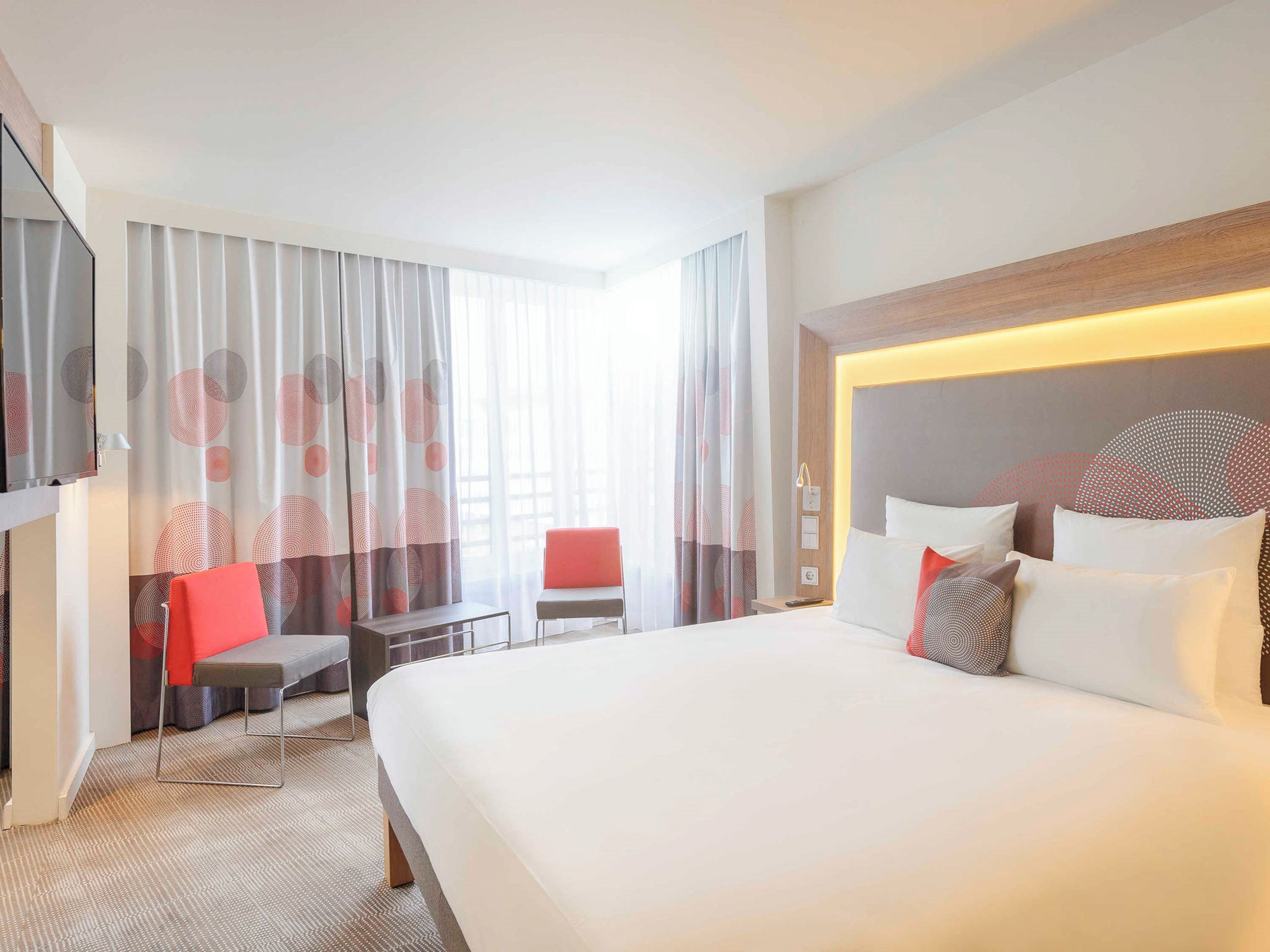 Ein Hotelzimmer mit einem großen Bett, einem Schreibtisch, einem Stuhl und einem Fernseher.