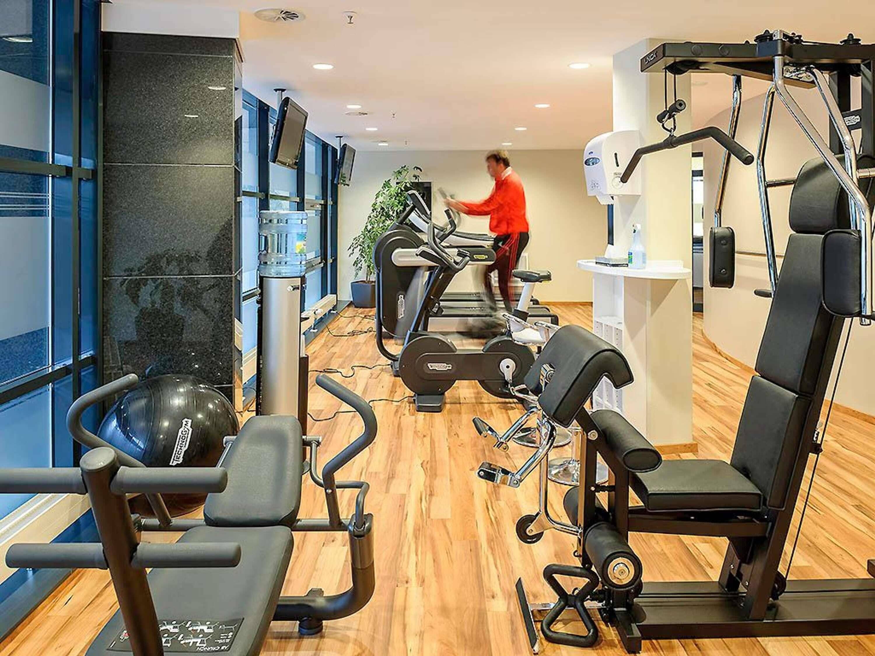A gym with cardio machines, weightlifting equipment, and a large exercise ball.