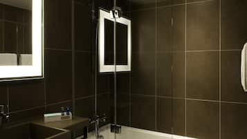 Un baño moderno con ducha envuelta en vidrio, un espejo grande y una bañera blanca.