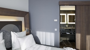 A hotel room with a bed, a bedside table, a mirror, and a bathroom visible through an open door. - Novotel Hannover (Hannover)