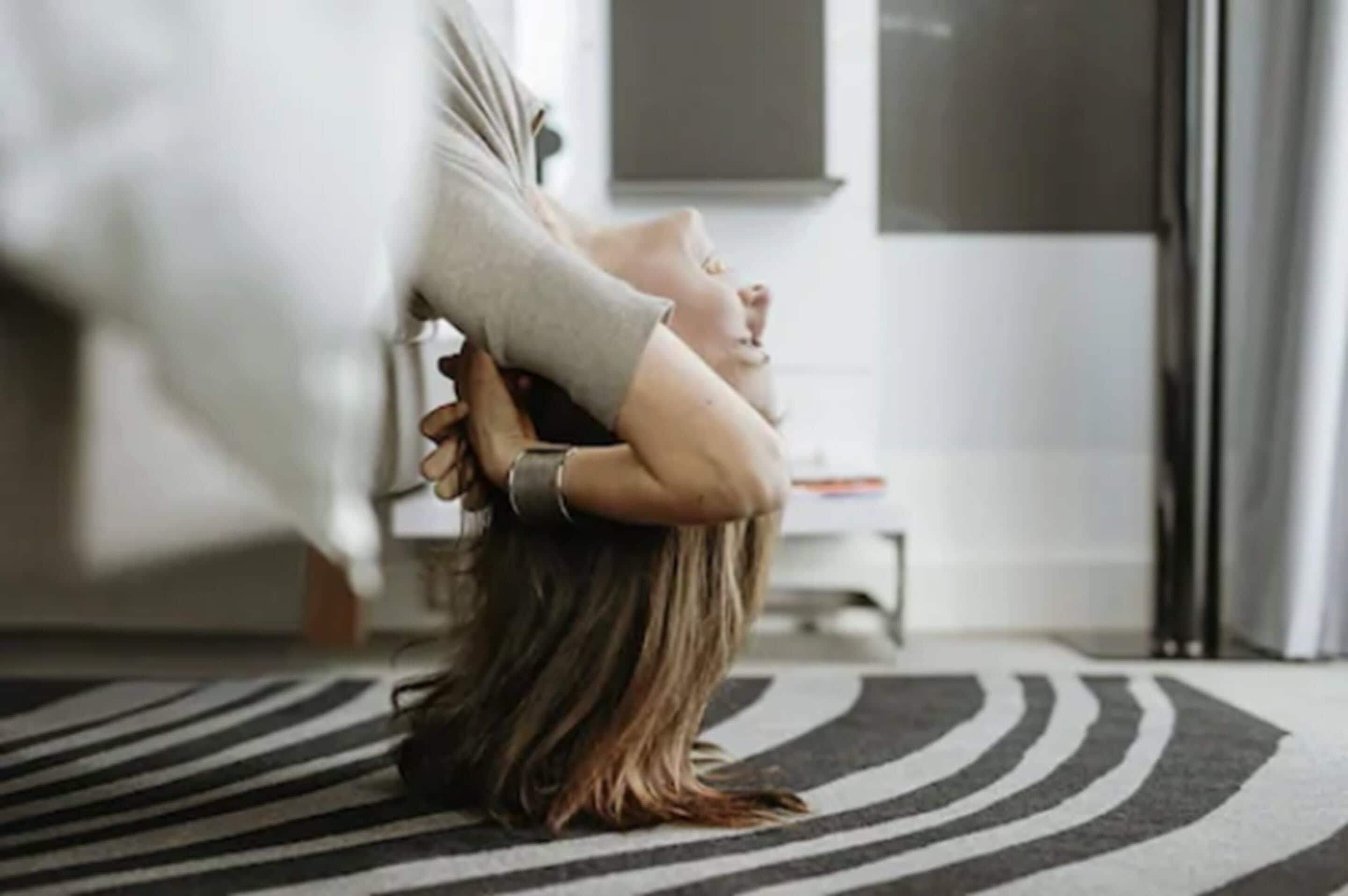 A person sitting on the floor with a striped rug, a white chair, and a white wall in the background.