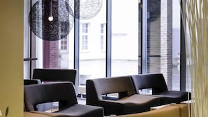 A modern interior with black and beige chairs, a wooden table, and a hanging light fixture. - Novotel Hannover (Hannover)