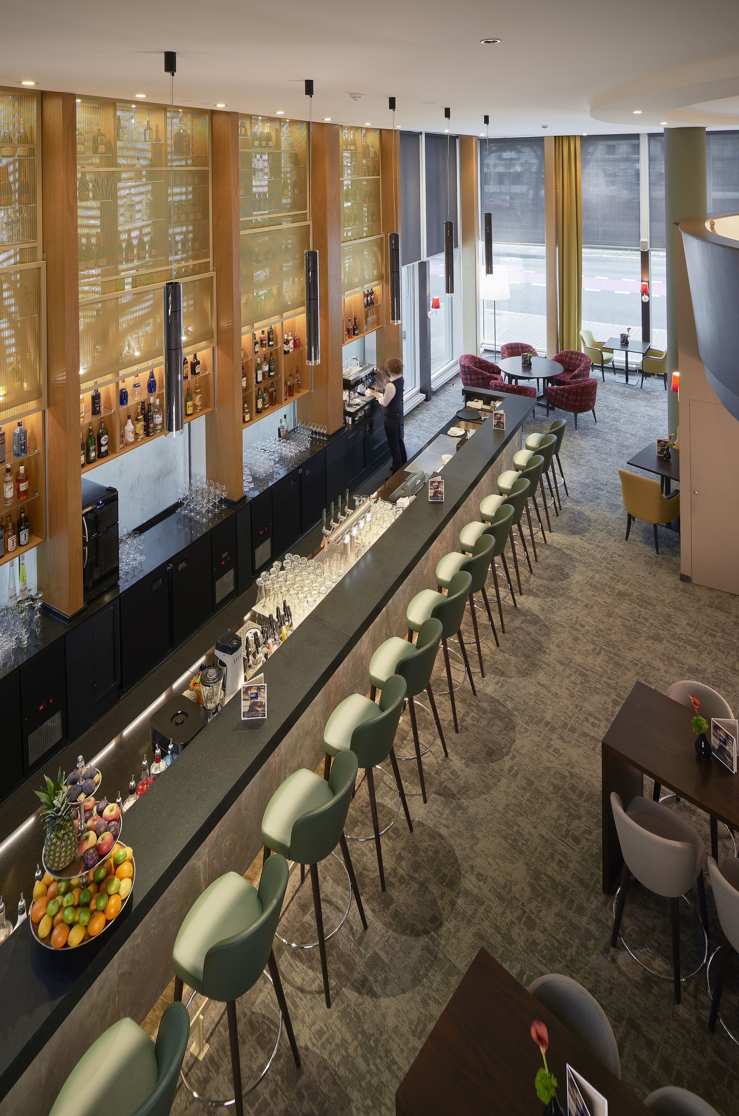 Eine Bar mit einer langen Theke, Barhocker und einer Obstauslage.