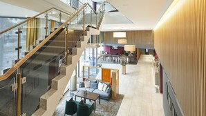 A spacious lobby with a staircase, seating area, and a television screen. - Dorint Kongresshotel Mannheim (Mannheim)