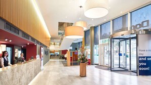 A modern hotel lobby with a reception desk, a glass booth, and a large potted plant. - Dorint Kongresshotel Mannheim (Mannheim)