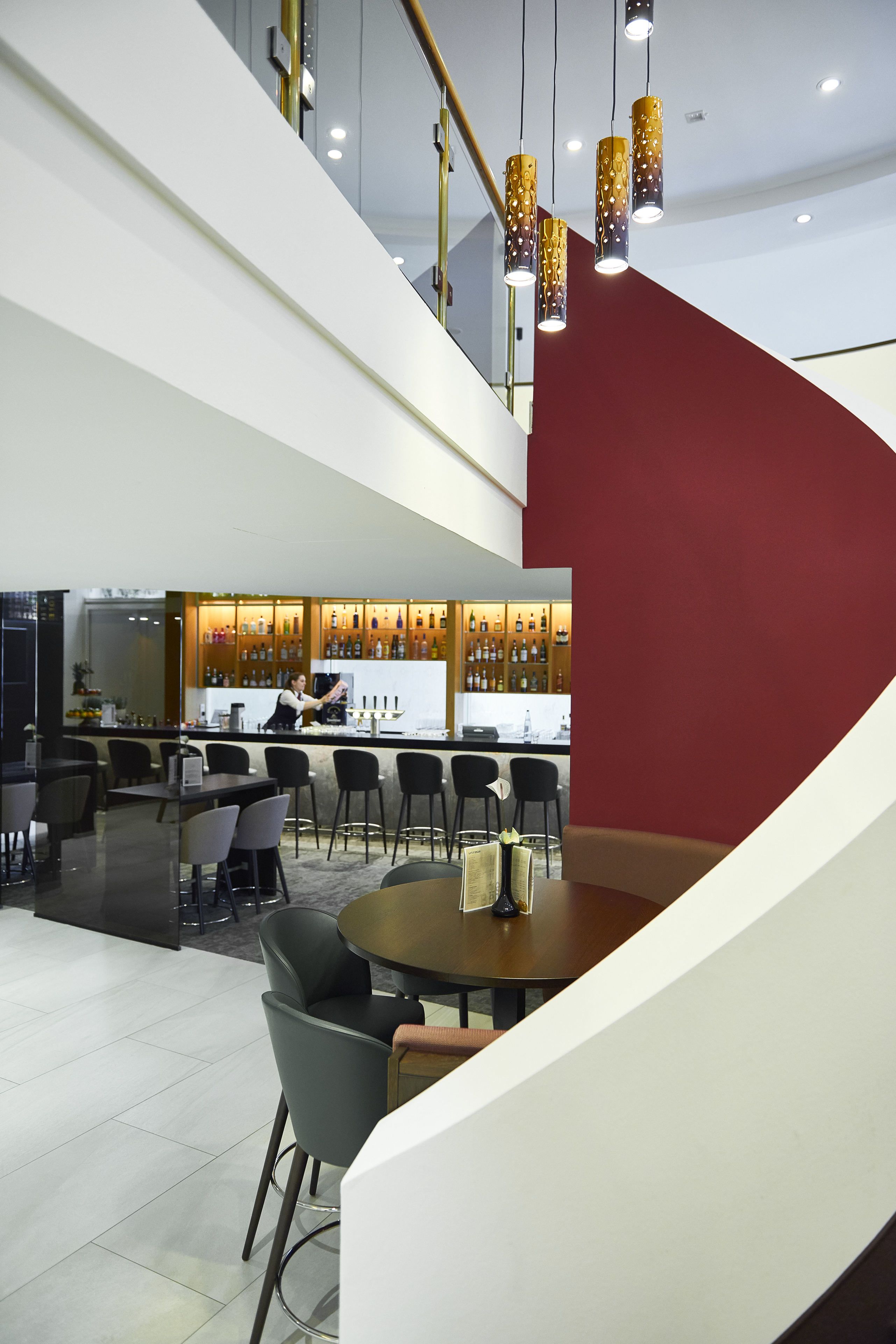 Um interior moderno com área de bar, assentos e escada.