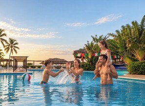 A swimming pool area with palm trees and a clear sky.