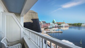 Un balcon offrant une vue sur une zone riveraine, comprenant un quai et des bâtiments aux styles architecturaux distincts.