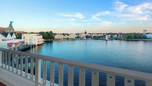 A waterfront hotel with a large building, a dock, and a statue in the background.