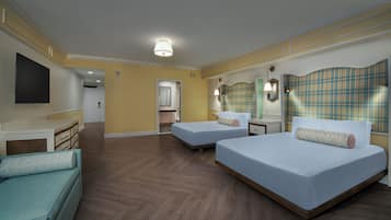 Quarto de hotel com duas camas, um sofá, uma escrivaninha e um banheiro visível por uma porta aberta.