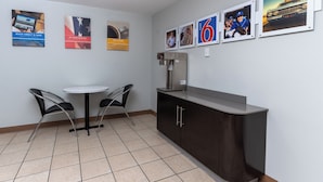 A small, modern kitchenette with a coffee machine, two chairs, and a table.