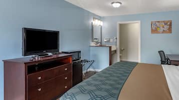 Habitación de hotel con cama, televisor, escritorio y cómoda.