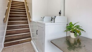 A staircase with wooden steps and white walls, a white washing machine, and a potted plant on a table. - Econo Lodge Inn & Suites Sandusky South (Sandusky)