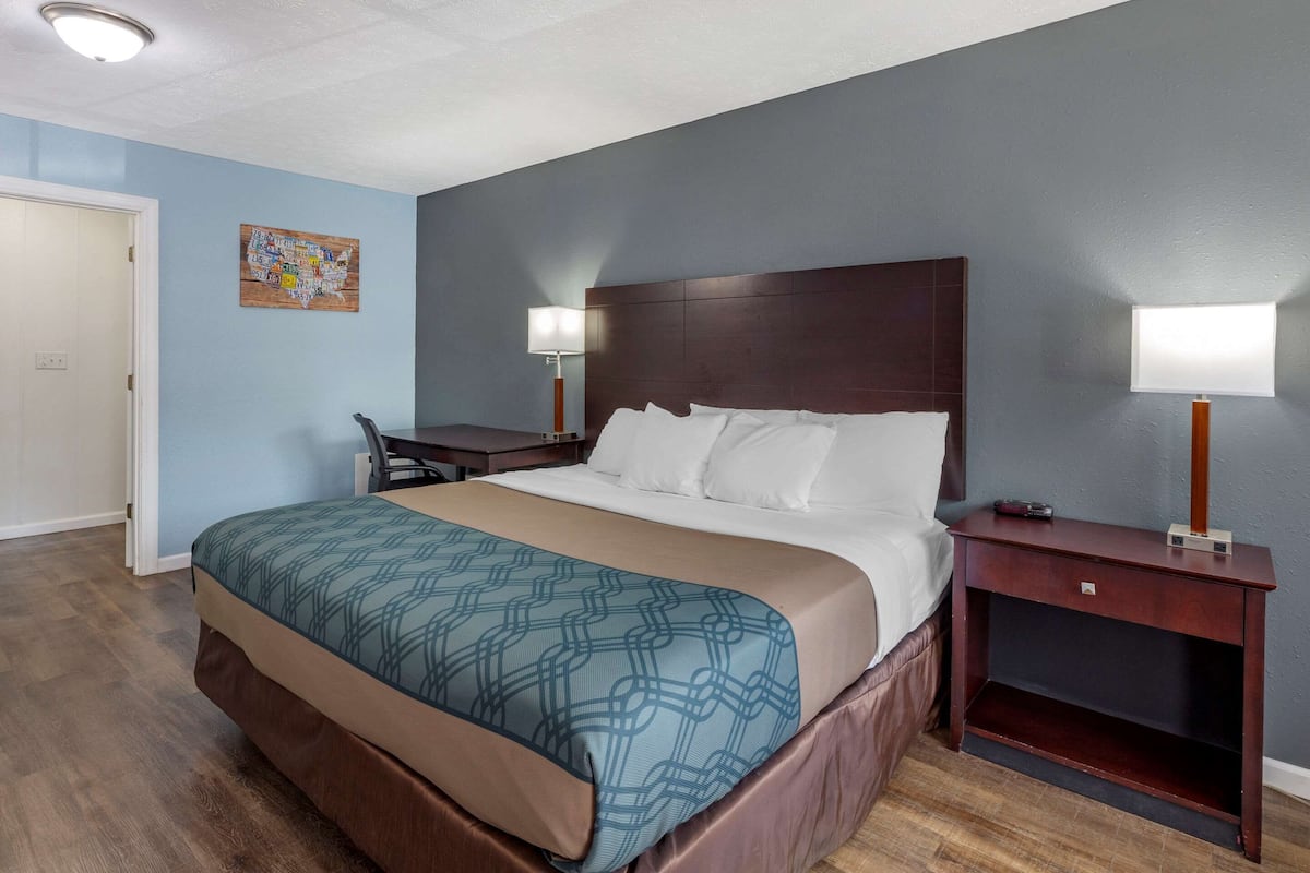 A hotel room with a bed, bedside tables, a desk, and a chair.