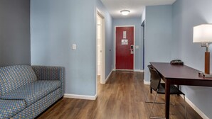 A room with a patterned sofa, a wooden dining table, and a red door. - Econo Lodge Inn & Suites Sandusky South (Sandusky)