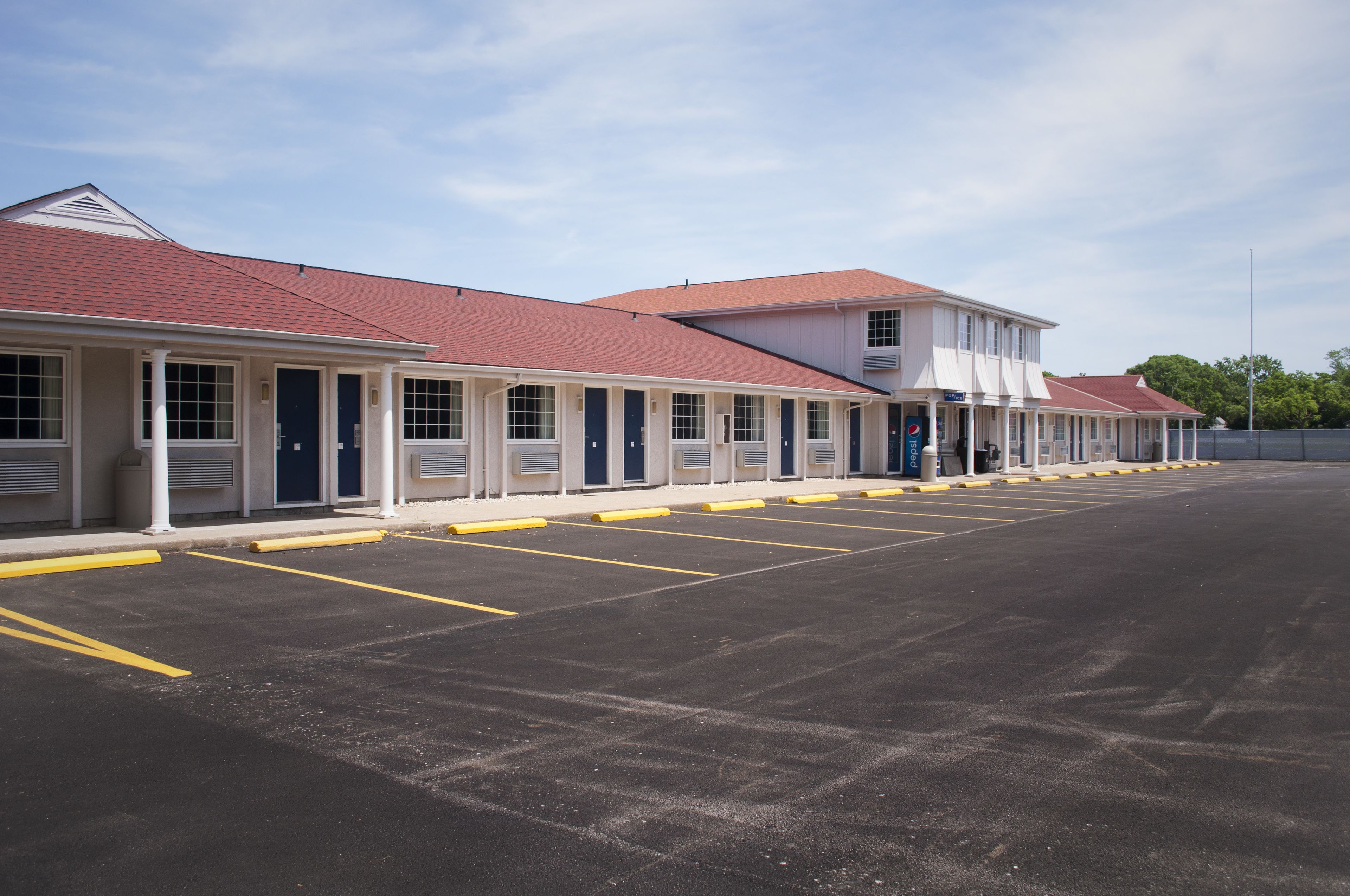 Una hilera de edificios tipo motel, con unidades individuales, cada una con puerta de garaje y estacionamiento techado.