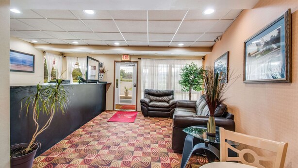 A hotel lobby with a reception desk, seating area, and a patterned carpet.