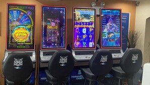 Four slot machines with a prominent logo on the chairs in front.