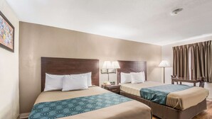 A hotel room with two beds, a desk, a chair, a lamp, and a painting on the wall.