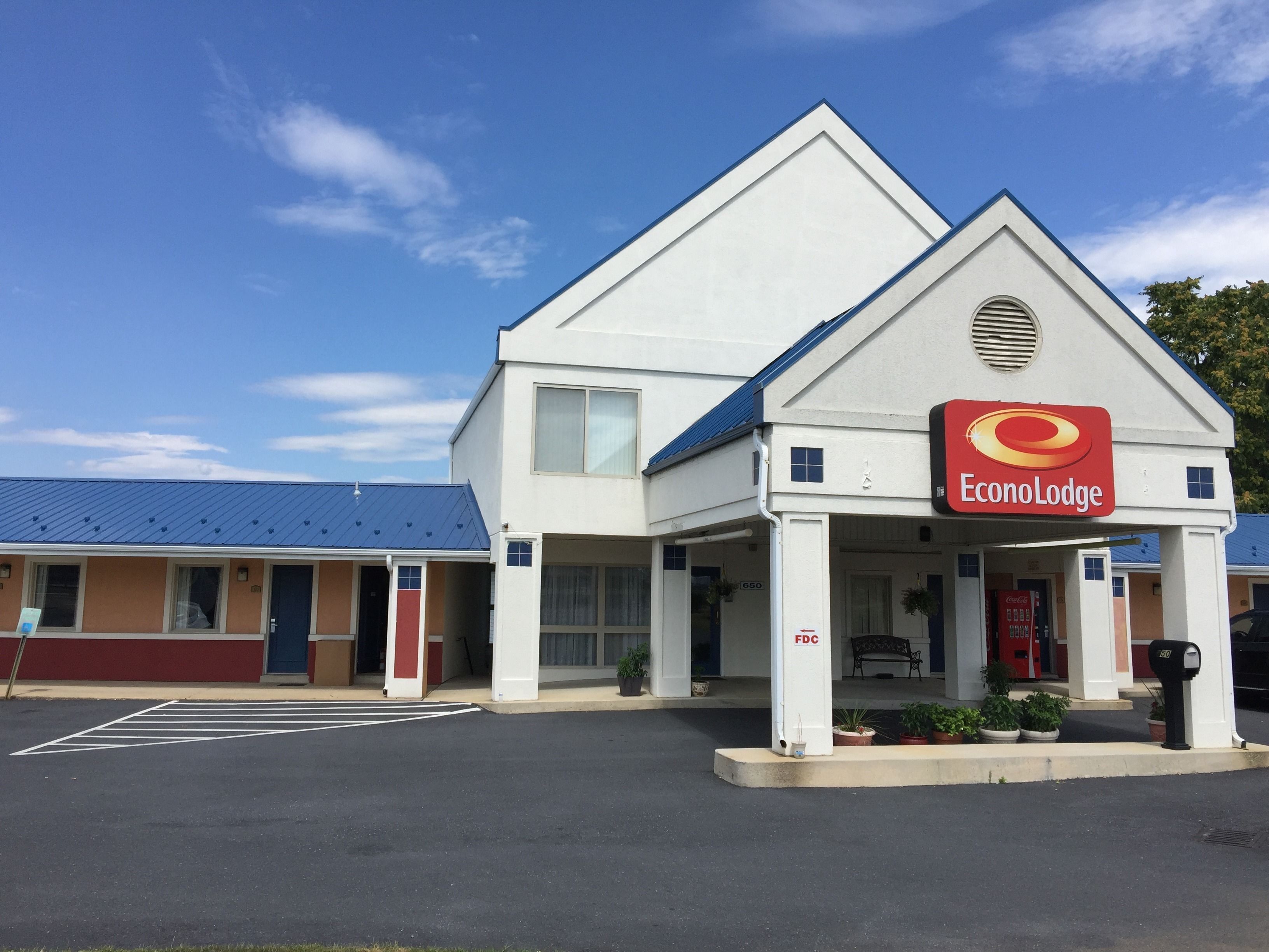 A two-story EconoLodge with a blue roof, a Coca-Cola vending machine, and a parking lot.