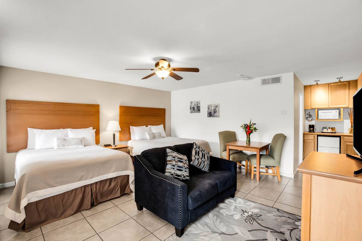 A hotel room with a bed, a sofa, a desk, and a television.