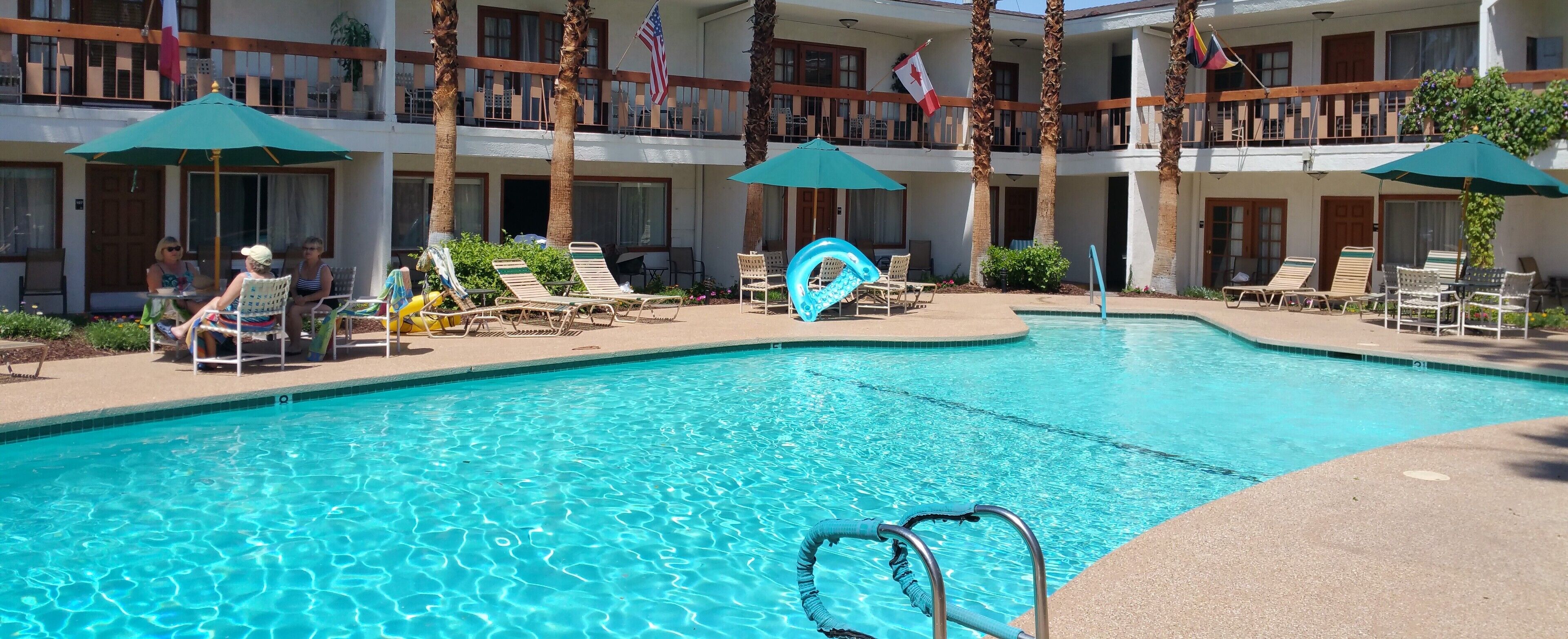 Ett poolområde vid hotellet med solstolar, parasoller och en klarblå pool.