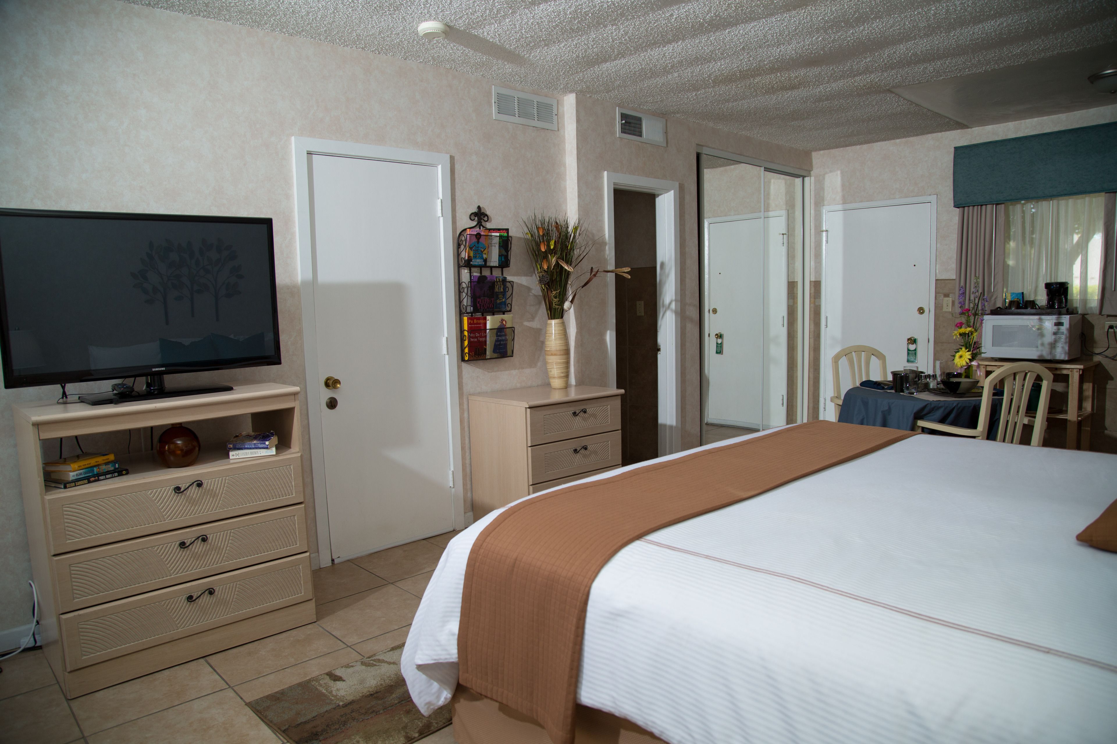 Une chambre d’hôtel équipée d’un lit, d’une télévision, d’un bureau avec une chaise et d’une petite table avec un four à micro-ondes.