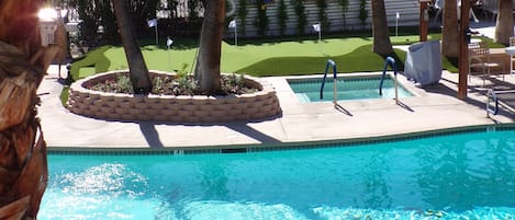 A swimming pool with a surrounding garden, a covered seating area, and a flag indicating a golf course nearby.