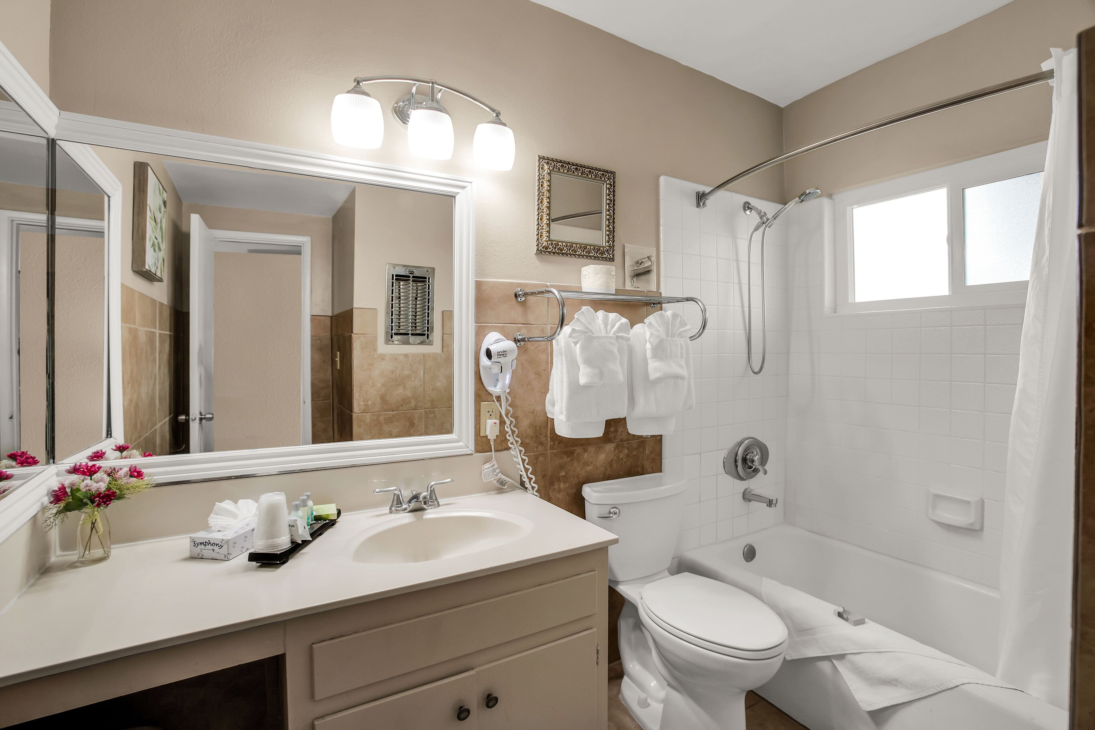 A bathroom with a sink, mirror, toilet, and shower.