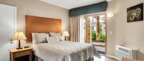 A hotel room with a bed, nightstands, a ceiling fan, a view of the outdoors, and a wall-mounted heater.